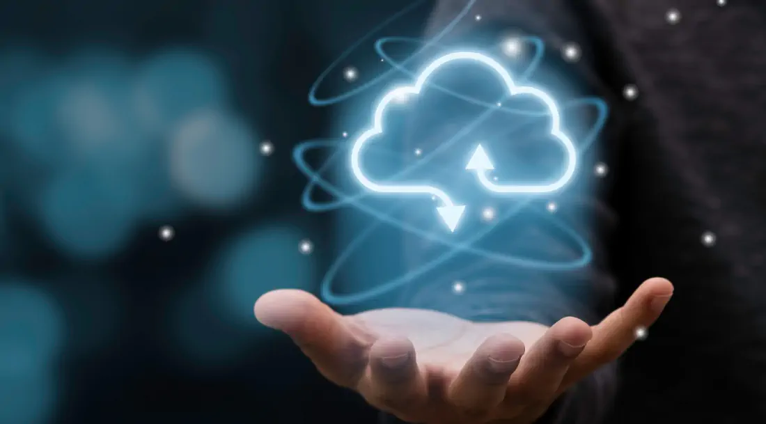 Conceptual image of a cloud computing icon with data transfer arrows floating above an open hand – symbolizing digital transformation and cloud services.