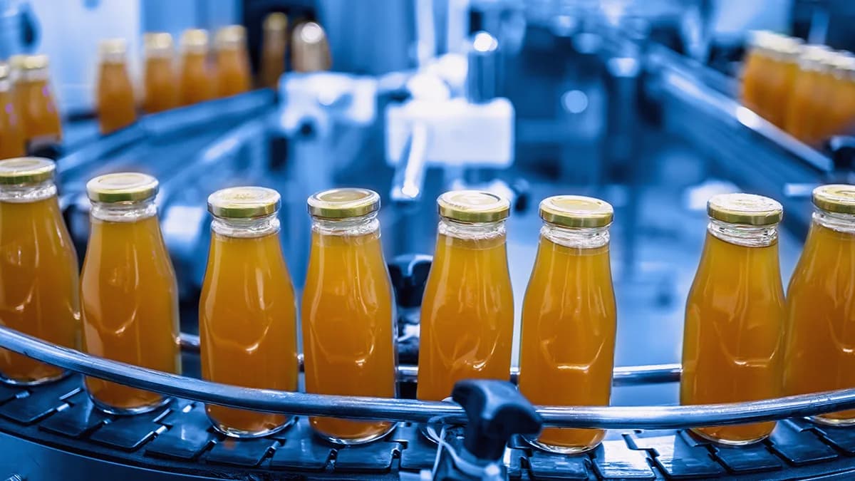 Production line in an FMCG factory using Unified Namespace for smarter recipe management — orange juice bottles being filled and monitored in real time through integrated MES and PLC systems.