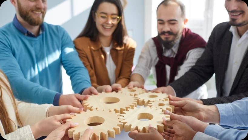 團隊手持象徵合作與融合的木製齒輪。