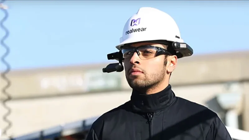 Zwei Kollegen arbeiten gemeinsam an einem Computer, wobei einer auf den Bildschirm zeigt.