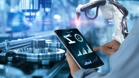 Engineer monitoring robotic machinery on a tablet.