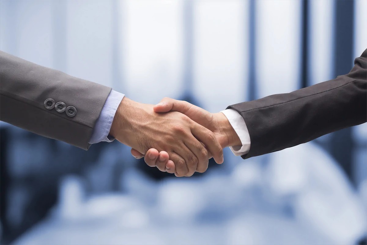 Handshake between two businessmen in suits symbolizing partnership.