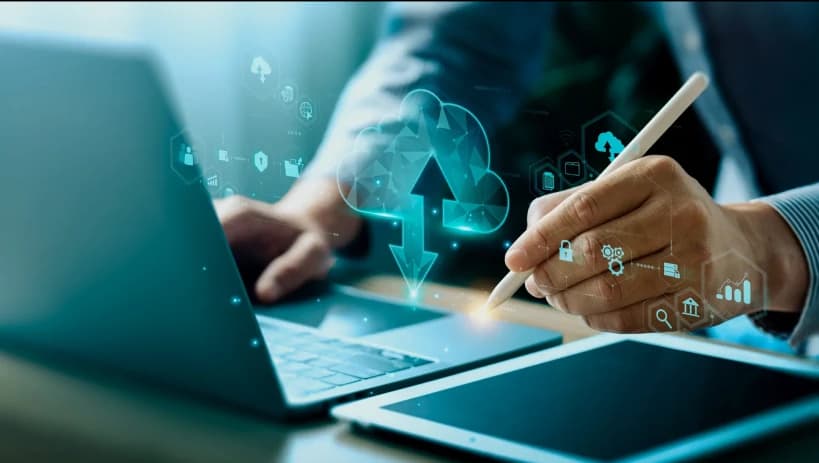 Business professional using a laptop and tablet, with a digital cloud computing concept overlay, symbolizing PLM (Product Lifecycle Management) in the cloud.